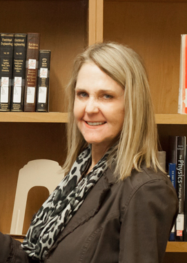 Connie Anderson smiling in front of book shelves.